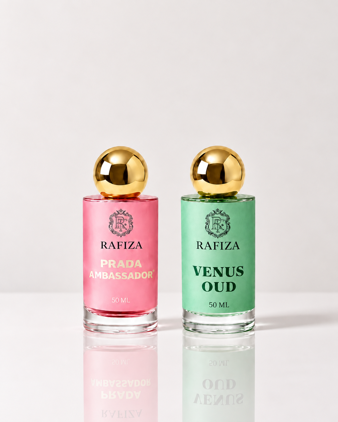 Two 50ml Rafiza perfume bottles on a reflective white surface against a light gray background. The left bottle is pink with gold lettering reading 'PRADA AMBASSADOR'.