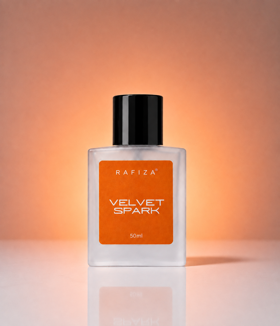 A 50ml bottle of Rafiza Velvet Spark fragrance, featuring a clear glass body, a black cap, and a prominent orange label, set against a warm peach gradient background with a soft reflection below.